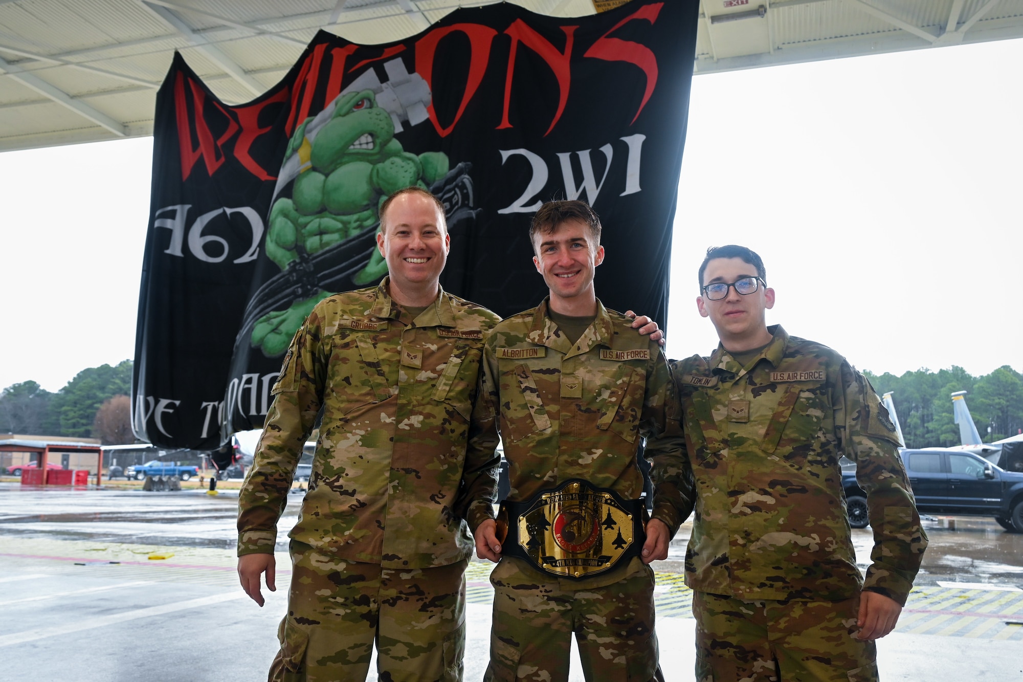 U.S. Air Force Senior Airman Tyler Grubbs, left, Airman Aiden Albritton, and Airman 1st Class Seth Tomlin, right, all assisted dedicated crew chiefs assigned to the 333rd Fighter Generation Squadron, pose for a photo after winning 1st place at an annual load crew competition at Seymour Johnson Air Force Base, North Carolina, on February 23, 2024. (U.S. Air Force photo by Staff Sgt. Koby I. Saunders)