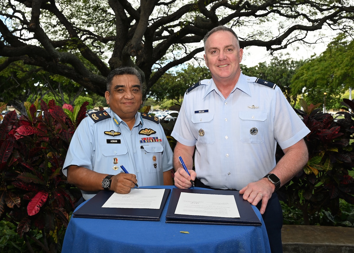 U.S. Air Force Brig. Gen. Gent Welsh, Washington Air National Guard commander, and Brig. Gen. Azman bin Jantan, deputy assistant chief of staff operations and strategy of the Royal Malaysian Air Force, sign a sister squadron agreement at Pacific Air Forces Headquarters, Joint Base Pearl Harbor-Hickman, Hawaii, Feb. 22, 2024. This agreement formalizes the enduring relationship between the Royal Malaysian Air Force’s 320 Squadron, Control and Reporting Center 1, and the Washington Air National Guard’s 225th Air Defense Group, Western Air Defense Sector.