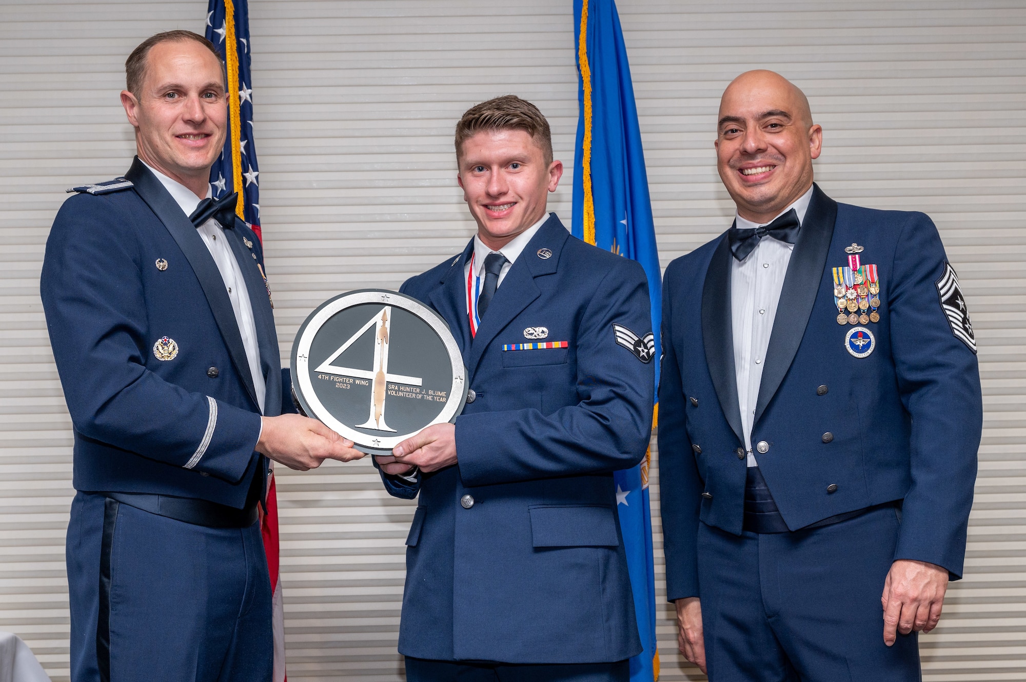 Senior Airman Hunter Blume, center, 335th Fighter Generation Squadron electrical and environmental journeyman, receives the Volunteer of the Year Award from Col. Lucas Teel, 4th Fighter Wing commander and Chief Master Sgt. Peter Martinez, 4 FW command chief, during the 4 FW Annual Awards ceremony and banquet at Seymour Johnson Air Force Base, North Carolina, Feb. 9, 2024. Annual Awards are awarded to Airmen and civilians in 13 different categories, including Volunteer of the Year, Senior Non-Commissioned Officer of the Year, Key Spouse of the Year, Airman of the Year and more. (U.S. Air Force photo by Senior Airman Sabrina Fuller-Judd)