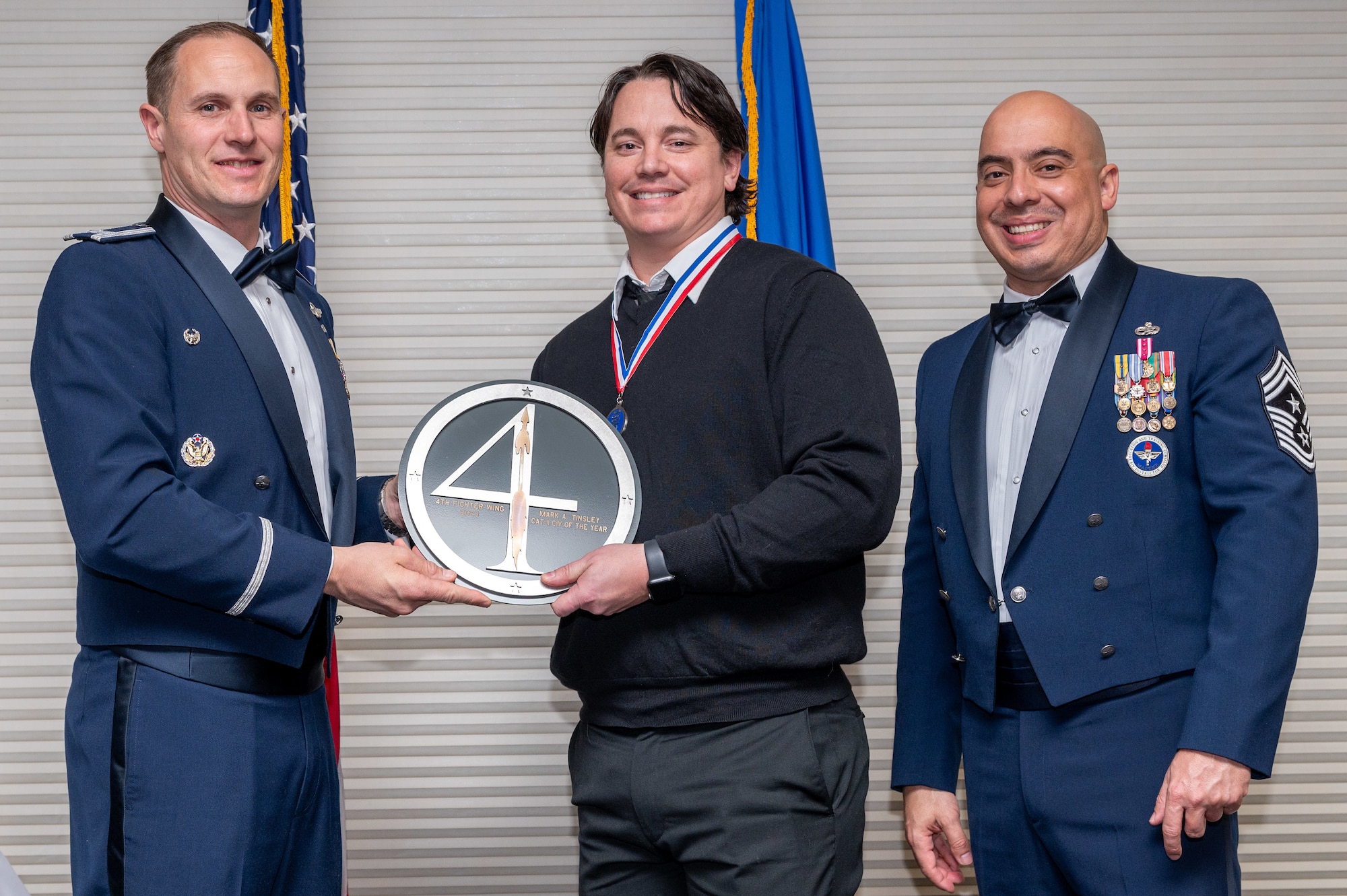 Mark Tinsley, center, 4th Wing Staff Agency information technology project manager, receives the Category 2 Civilian of the Year Award from Col. Lucas Teel, 4th Fighter Wing commander and Chief Master Sgt. Peter Martinez, 4 FW command chief, during the 4 FW Annual Awards ceremony and banquet at Seymour Johnson Air Force Base, North Carolina, Feb. 9, 2024. Annual Awards are awarded to Airmen and civilians in 13 different categories, including Volunteer of the Year, Senior Non-Commissioned Officer of the Year, Key Spouse of the Year, Airman of the Year and more. (U.S. Air Force photo by Senior Airman Sabrina Fuller-Judd)