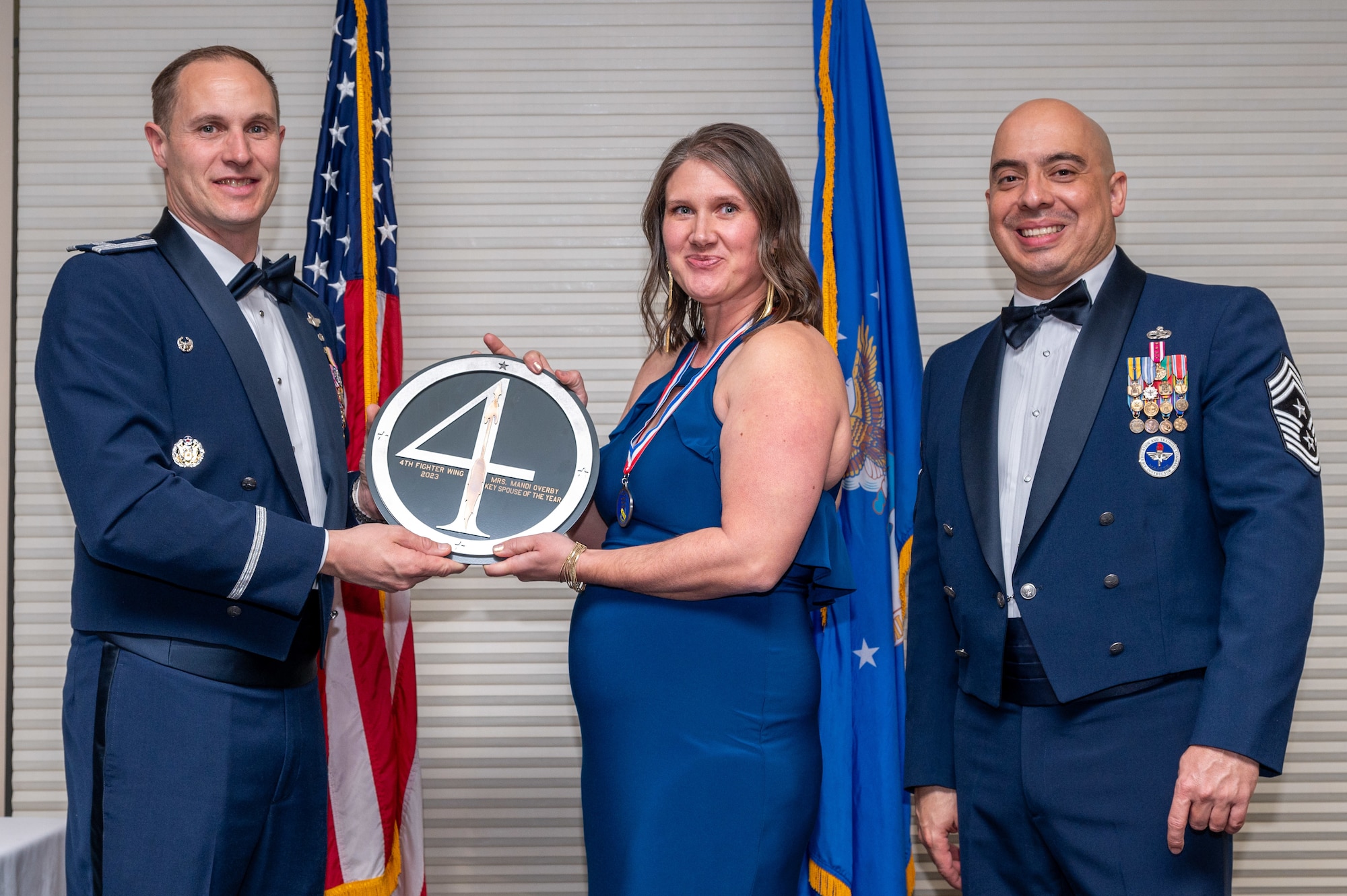Mrs. Mandi Overby, center, 336th Fighter Generation Squadron key spouse, receives the Key Spouse of the Year Award from Col. Lucas Teel, 4th Fighter Wing commander and Chief Master Sgt. Peter Martinez, 4 FW command chief, during the 4 FW Annual Awards ceremony and banquet at Seymour Johnson Air Force Base, North Carolina, Feb. 9, 2024. Annual Awards are awarded to Airmen and civilians in 13 different categories, including Volunteer of the Year, Senior Non-Commissioned Officer of the Year, Key Spouse of the Year, Airman of the Year and more. (U.S. Air Force photo by Senior Airman Sabrina Fuller-Judd)