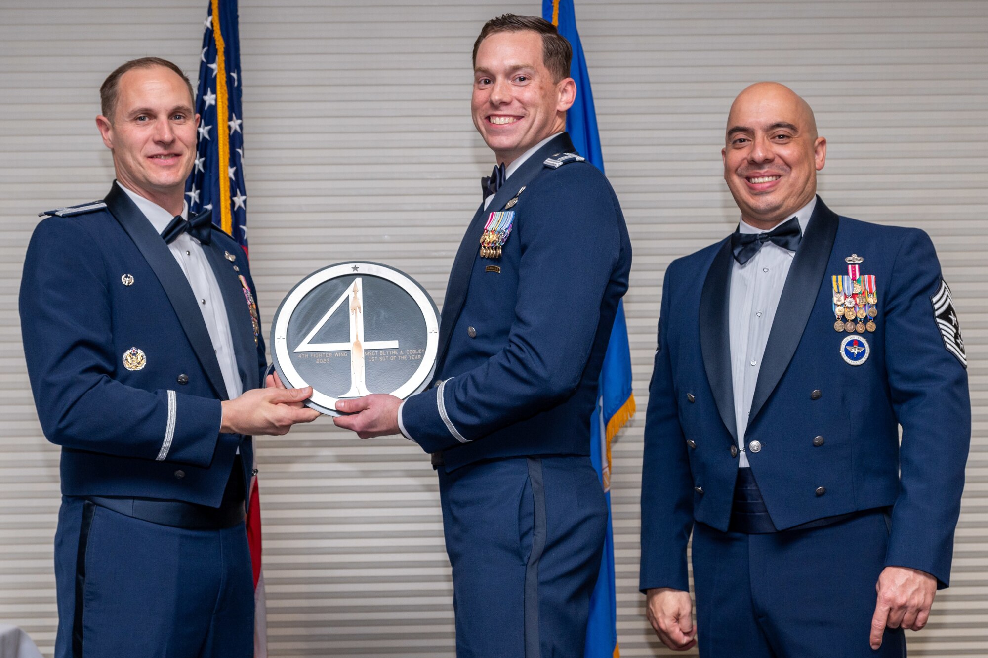 Master Sgt. Blythe Cooley, center, 4th Security Forces Squadron First Sergeant, receives the First Sergeant of the Year Award from Col. Lucas Teel, 4th Fighter Wing commander and Chief Master Sgt. Peter Martinez, 4 FW command chief, during the 4 FW Annual Awards ceremony and banquet at Seymour Johnson Air Force Base, North Carolina, Feb. 9, 2024. Annual Awards are awarded to Airmen and civilians in 13 different categories, including Volunteer of the Year, Senior Non-Commissioned Officer of the Year, Key Spouse of the Year, Airman of the Year and more. (U.S. Air Force photo by Senior Airman Sabrina Fuller-Judd)