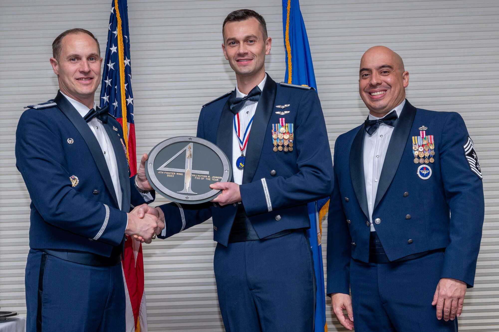 Maj. Nathan Johnson, center, 4th Fighter Wing A-Staff operations director, receives the Field Grade Officer of the Year Award from Col. Lucas Teel, 4 FW commander and Chief Master Sgt. Peter Martinez, 4 FW command chief, during the 4 FW Annual Awards ceremony and banquet at Seymour Johnson Air Force Base, North Carolina, Feb. 9, 2024. Annual Awards are awarded to Airmen and civilians in 13 different categories, including Volunteer of the Year, Senior Non-Commissioned Officer of the Year, Key Spouse of the Year, Airman of the Year and more. (U.S. Air Force photo by Senior Airman Sabrina Fuller-Judd)