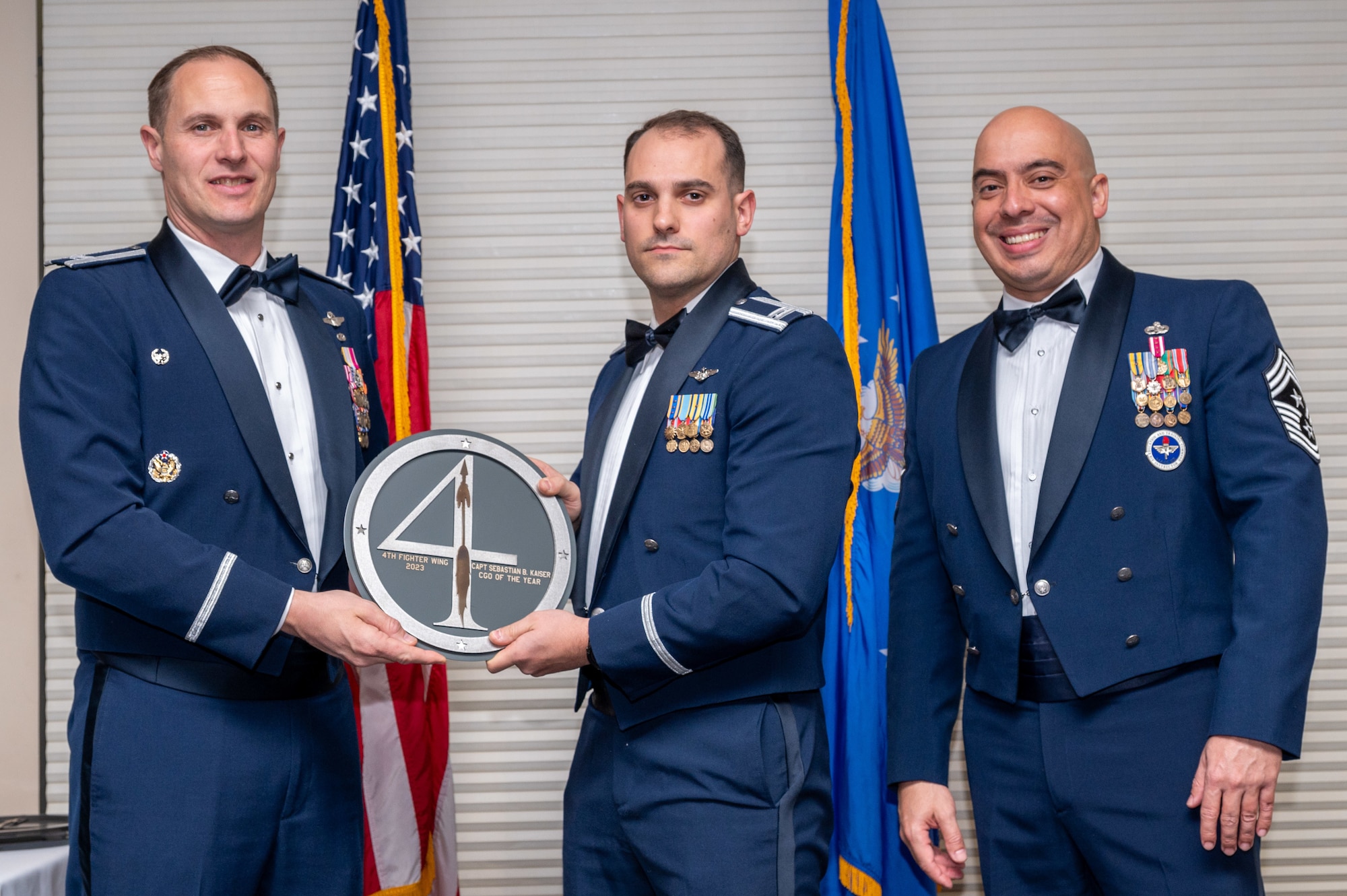 Capt. Sebastian Kaiser, center, 4th Fighter Wing A-Staff chief of current operations, receives the Company Grade Officer of the Year Award from Col. Lucas Teel, 4 FW commander and Chief Master Sgt. Peter Martinez, 4 FW command chief, during the 4 FW Annual Awards ceremony and banquet at Seymour Johnson Air Force Base, North Carolina, Feb. 9, 2024. Annual Awards are awarded to Airmen and civilians in 13 different categories, including Volunteer of the Year, Senior Non-Commissioned Officer of the Year, Key Spouse of the Year, Airman of the Year and more. (U.S. Air Force photo by Senior Airman Sabrina Fuller-Judd)