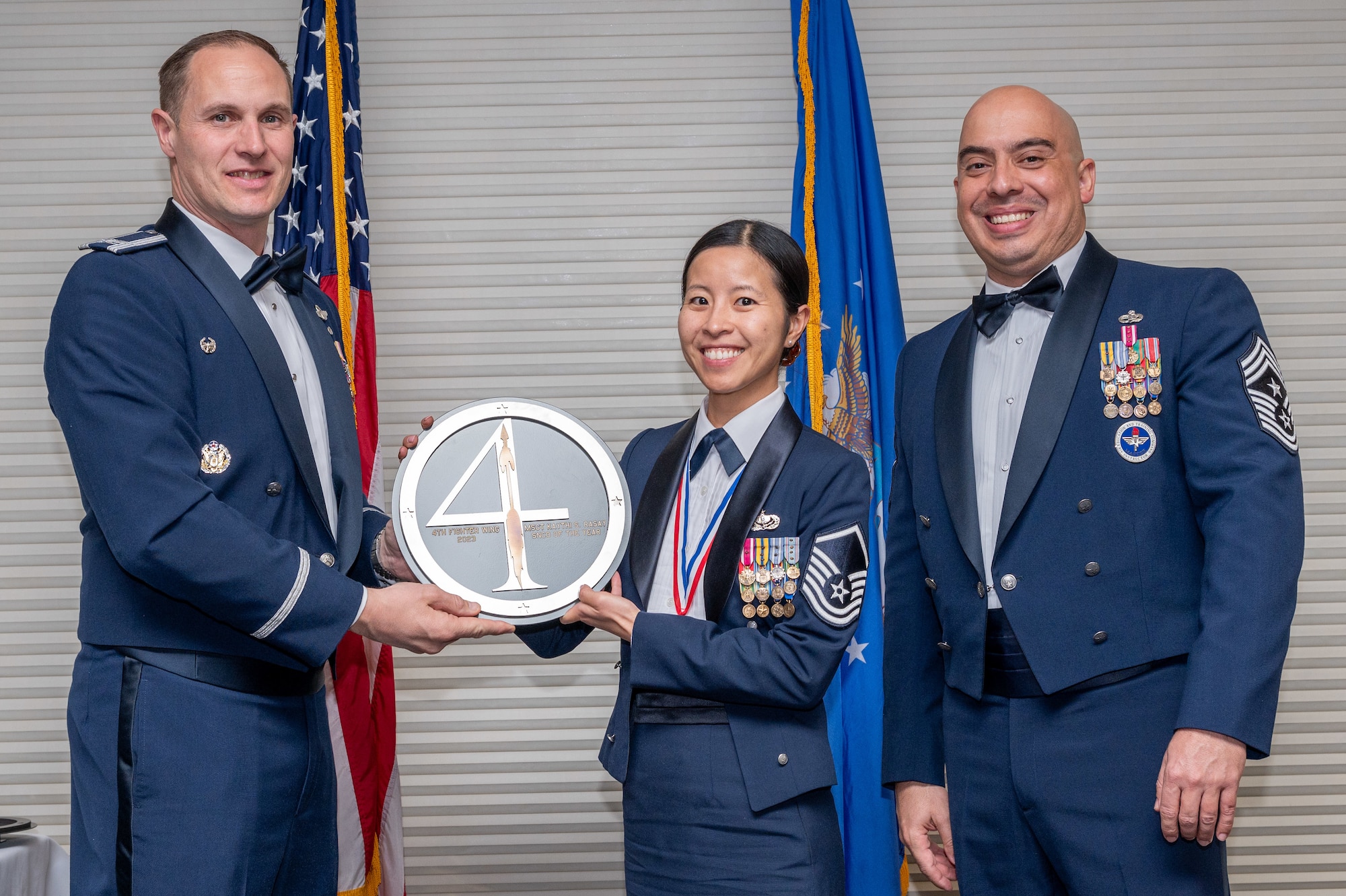 Master Sgt. Kaythi Rasay, center, 4th Mission Support Group food service section chief, receives the Senior Non-commissioned Officer of the Year Award from Col. Lucas Teel, 4th Fighter Wing commander and Chief Master Sgt. Peter Martinez, 4 FW command chief, during the 4 FW Annual Awards ceremony and banquet at Seymour Johnson Air Force Base, North Carolina, Feb. 9, 2024. Annual Awards are awarded to Airmen and civilians in 13 different categories, including Volunteer of the Year, Senior Non-Commissioned Officer of the Year, Key Spouse of the Year, Airman of the Year and more. (U.S. Air Force photo by Senior Airman Sabrina Fuller-Judd)
