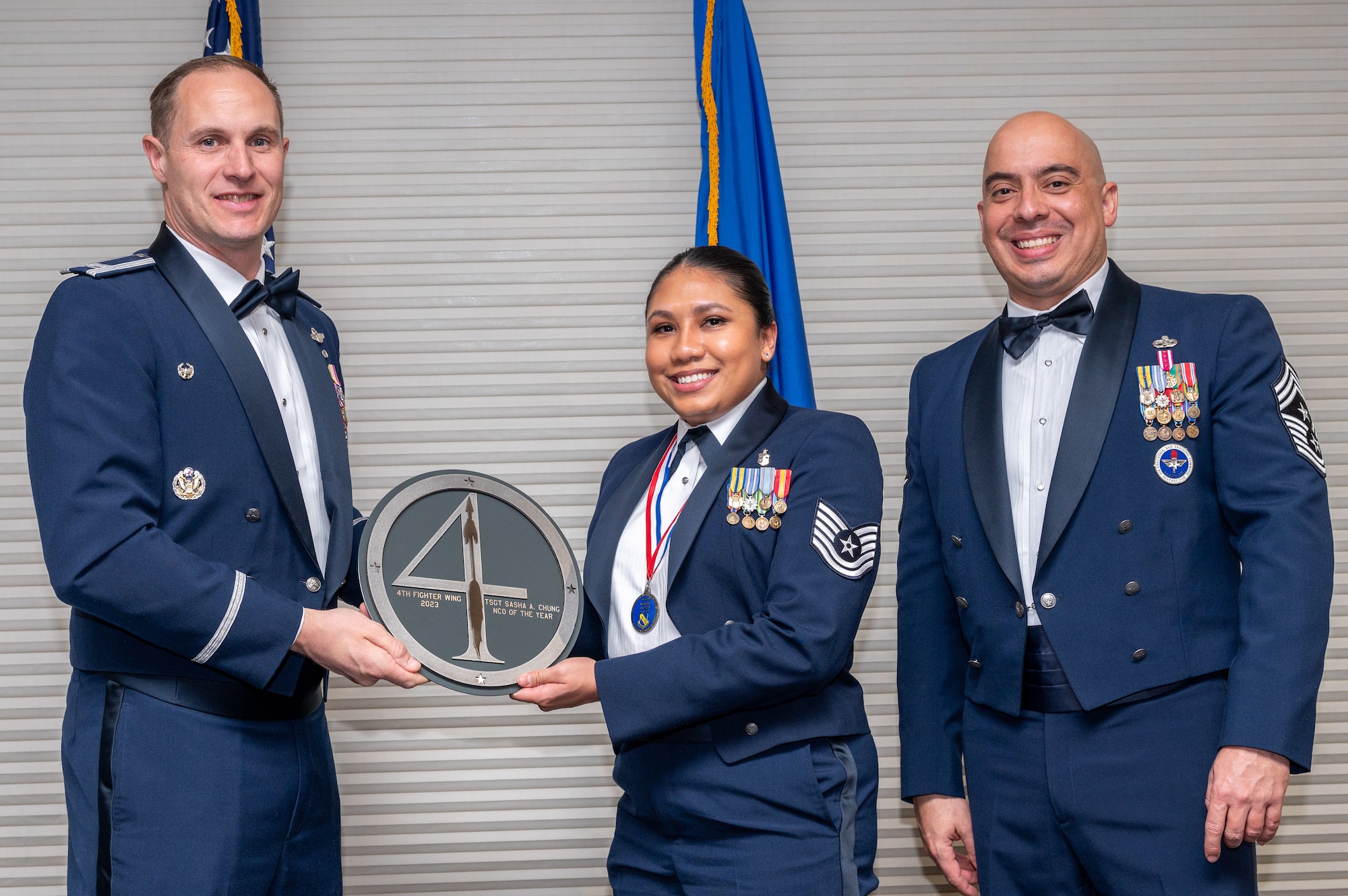 Tech. Sgt. Sasha Chung, center, 4th Medical Group Medical Support services flight chief, receives the Non-Commissioned Officer of the Year Award from Col. Lucas Teel, 4th Fighter Wing commander and Chief Master Sgt. Peter Martinez, 4 FW command chief, during the 4 FW Annual Awards ceremony and banquet at Seymour Johnson Air Force Base, North Carolina, Feb. 9, 2024. Annual Awards are awarded to Airmen and civilians in 13 different categories, including Volunteer of the Year, Senior Non-Commissioned Officer of the Year, Key Spouse of the Year, Airman of the Year and more. (U.S. Air Force photo by Senior Airman Sabrina Fuller-Judd)