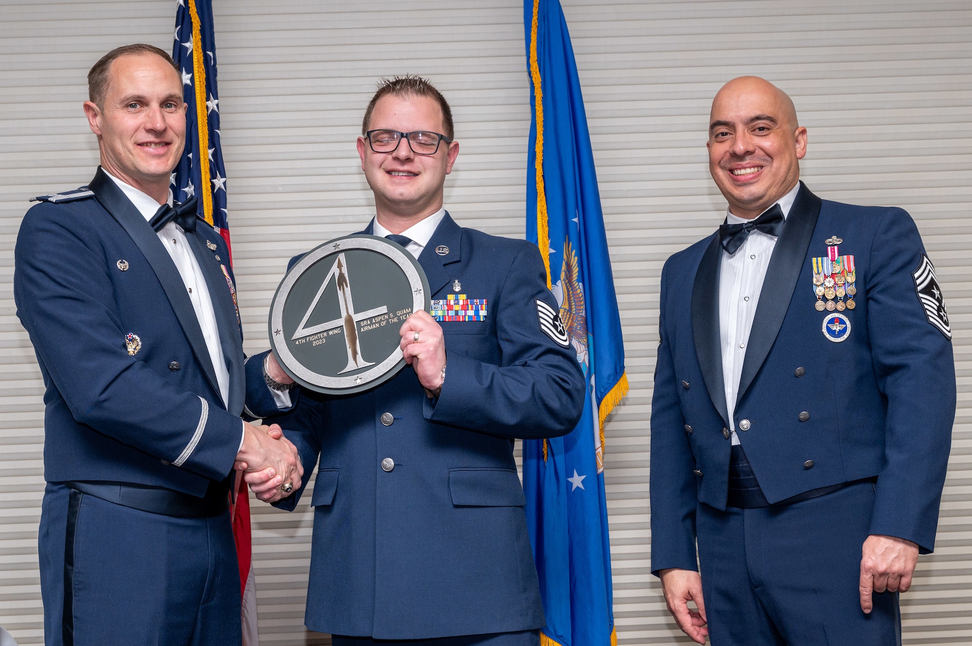 Staff Sgt. Aspen Quam, center, 4th Medical Group Non-Commissioned Officer in Charge of occupational health, receives the Airman of the Year Award from Col. Lucas Teel, 4th Fighter Wing commander and Chief Master Sgt. Peter Martinez, 4 FW command chief, during the 4 FW Annual Awards ceremony and banquet at Seymour Johnson Air Force Base, North Carolina, Feb. 9, 2024. Annual Awards are awarded to Airmen and civilians in 13 different categories, including Volunteer of the Year, Senior Non-Commissioned Officer of the Year, Key Spouse of the Year, Airman of the Year and more. (U.S. Air Force photo by Senior Airman Sabrina Fuller-Judd)