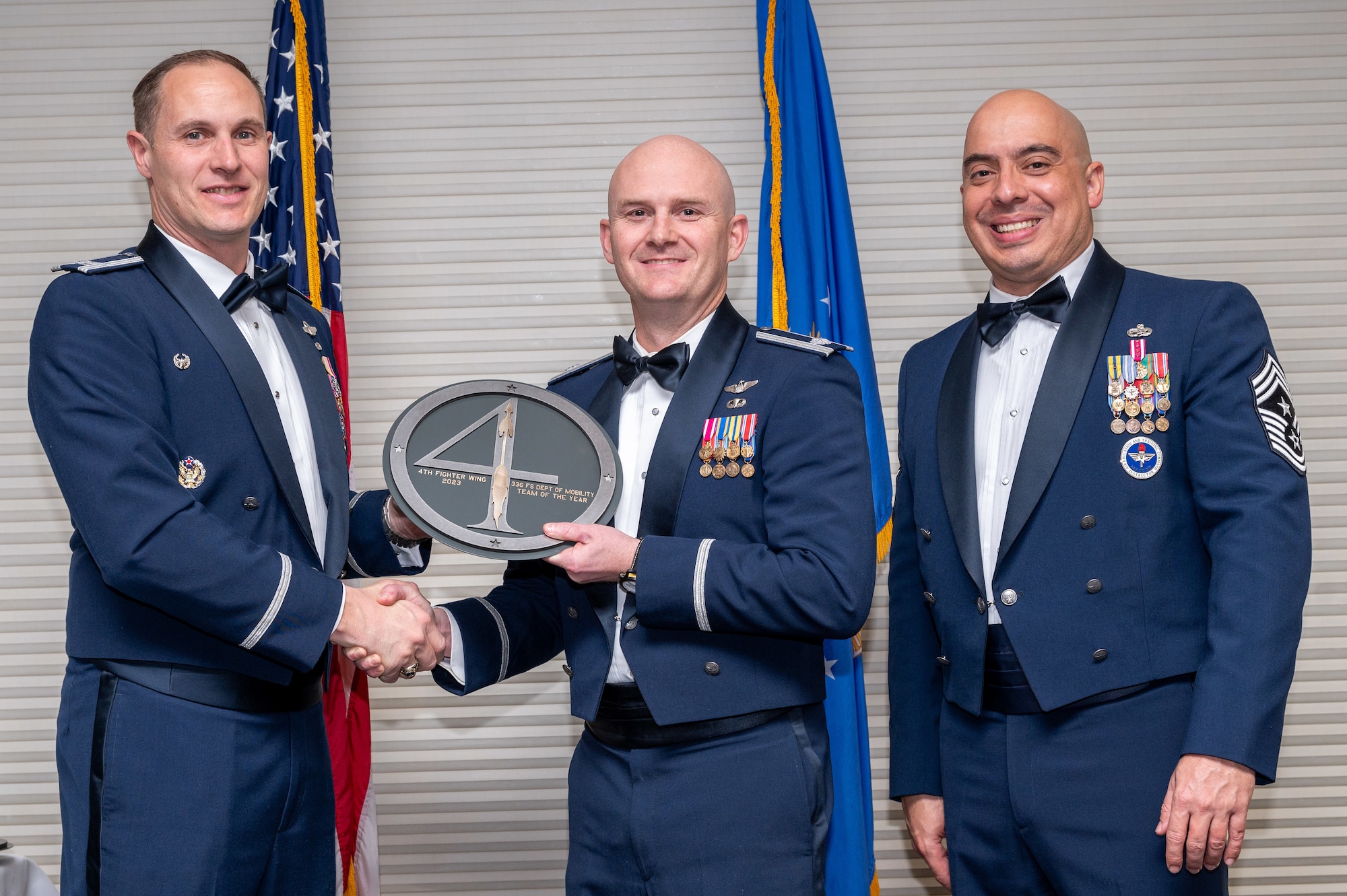 Lt. Col. Taylor Gifford, center, 336th Fighter Squadron commander, represents the 336th Fighter Squadron Department of Mobility in winning the 4th Fighter Wing Team of the Year Award from Col. Lucas Teel, 4 FW commander and Chief Master Sgt. Peter Martinez, 4 FW command chief, during the 4 FW Annual Awards ceremony and banquet at Seymour Johnson Air Force Base, North Carolina, Feb. 9, 2024. Annual Awards are awarded to Airmen and civilians in 13 different categories, including Volunteer of the Year, Senior Non-Commissioned Officer of the Year, Key Spouse of the Year, Airman of the Year and more. (U.S. Air Force photo by Senior Airman Sabrina Fuller-Judd)
