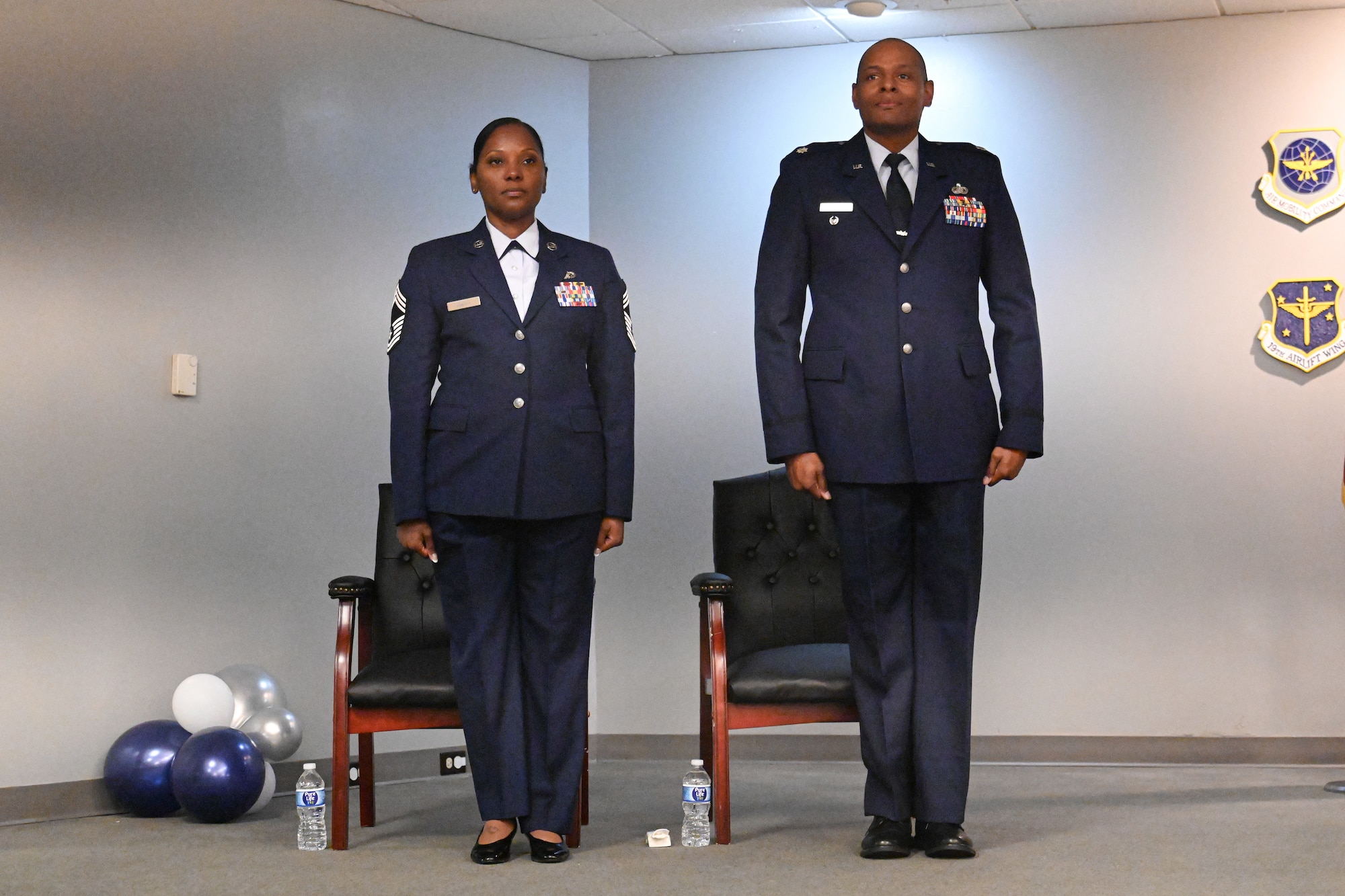 A man and woman in uniform stand at attention.