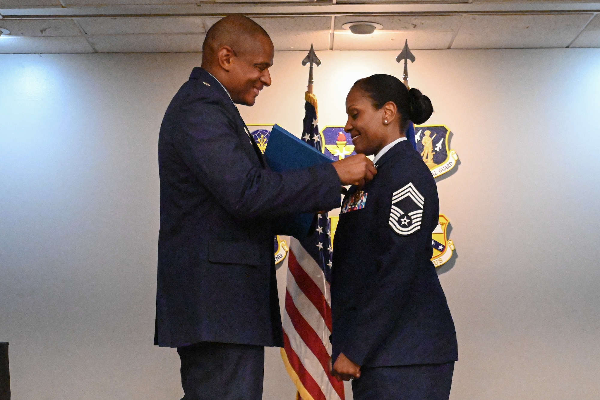 A man in uniform pins on a medal on a woman in uniform.