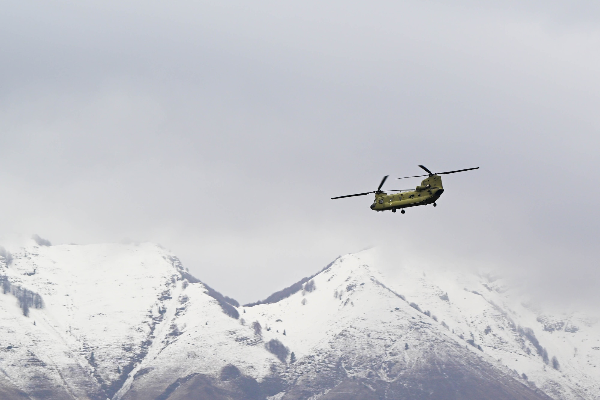 a helicopter is seen flying in front of snowy mountain tops