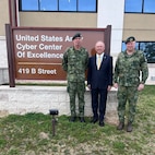 Three men standing in front of the Cyber Center of Excellence Sign