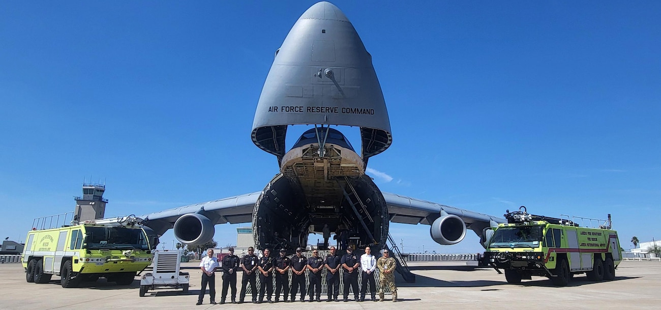 Laredo community fire fighters take a group photo with Senior Master Sgt. Steven Martinez, 433rd Operations Group chief standards and evaluations flight engineer, in front of a C-5M Super Galaxy before an airshow on the flightline at the Laredo International Airport, Texas Feb. 25, 2024.
