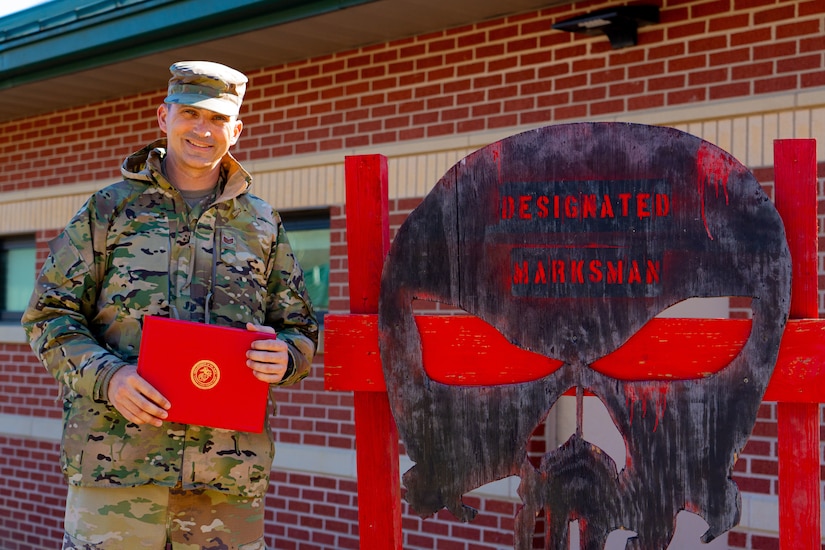 Airman stands beside a sign.