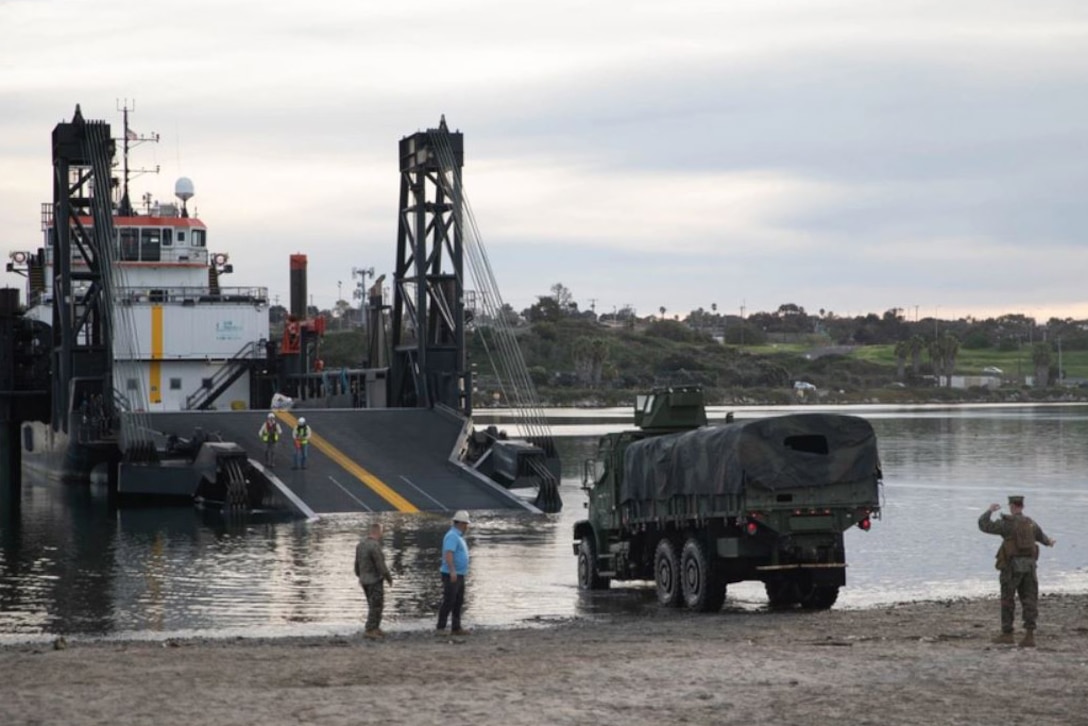A large transport vehicle traverses from land to a boat.