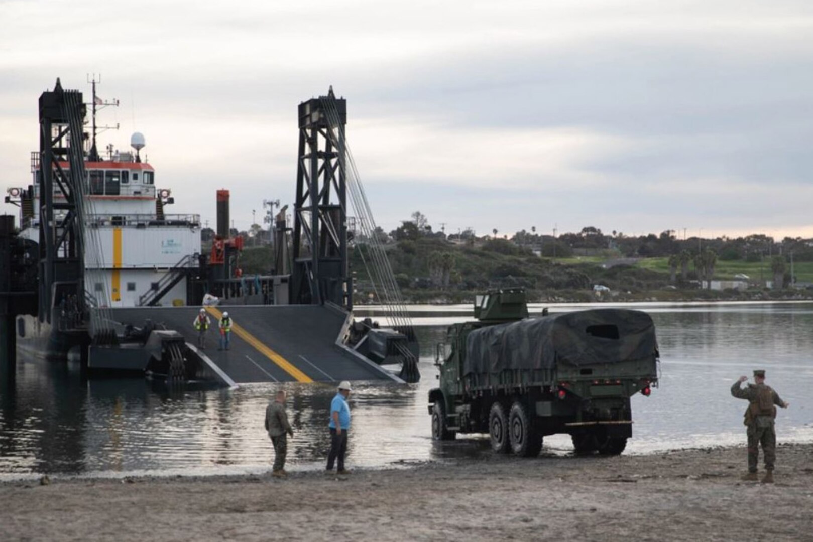 A large transport vehicle traverses from land to a boat.