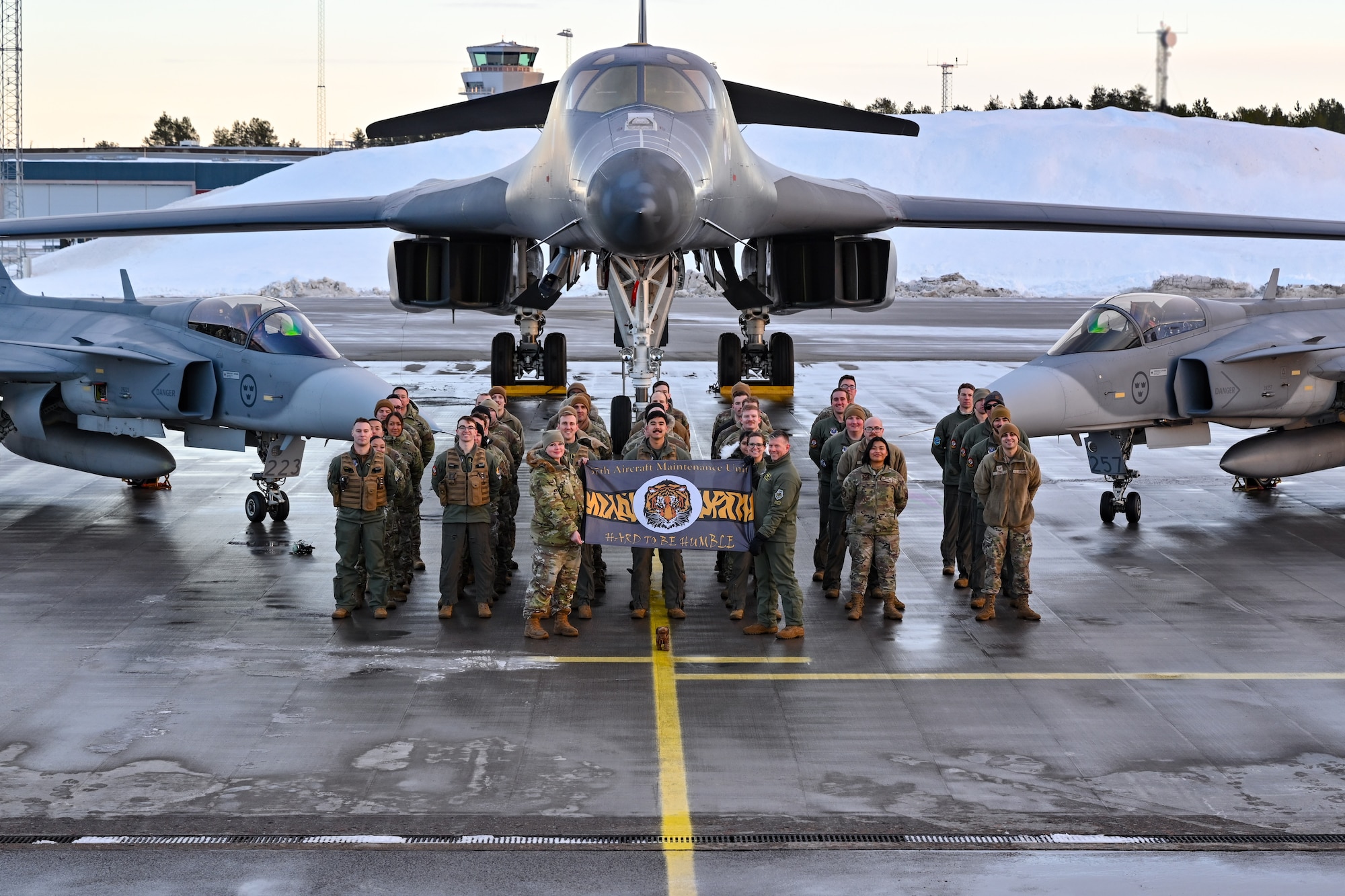 U.S. Air Force Airmen assigned to the 37th Bomb Squadron, Ellsworth Air Force Base, South Dakota, pose for a group photo in front of a B-1B Lancer and two Saab JAS 39 Gripens at Luleå-Kallax Air Base, Sweden, Feb. 26, 2024, during Bomber Task Force 24-2. These BTF missions are representative of the U.S.' extended deterrent commitment to its Allies and partners and enhance regional security. BTF operations provide U.S. leaders with strategic options to assure Allies and partners, while deterring potential adversary aggression across the globe. (U.S. Air Force photo by Staff Sgt. Jake Jacobsen)