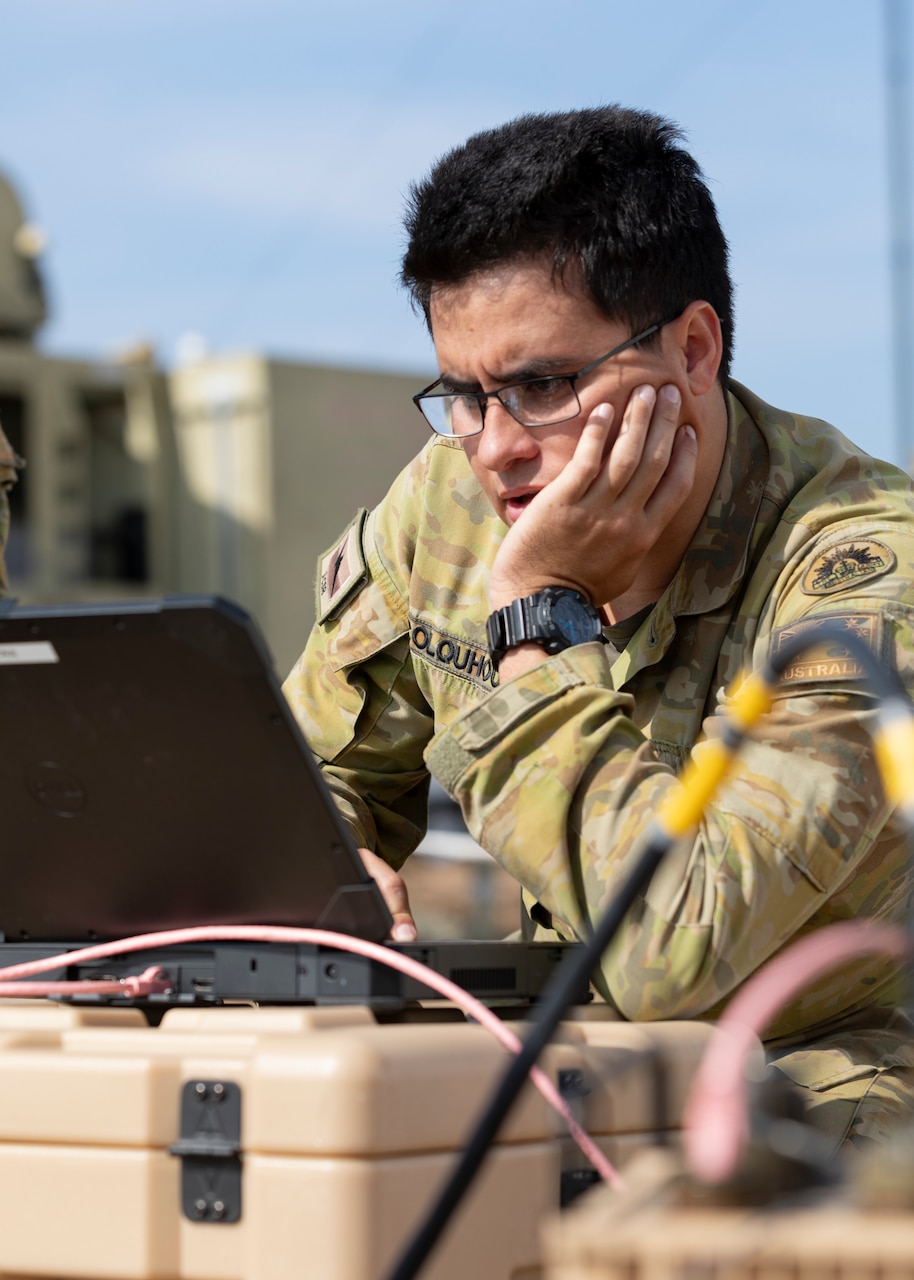 A man in uniform looks at laptop screen.