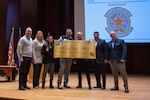 U.S. Army Maj. Rich Piltingsrud (center-left), strategic planner, Colorado Army National Guard, receives a $500 check as part of the Joint Enlistment Enhancement Program from U.S. Army Maj. Gen. Laura L. Clellan (center-right), the adjutant general of Colorado, at the University of Denver, Feb. 8, 2024. The JEEP program incentivizes current Colorado National Guard members to become more involved in referring and enlisting new members into the CONG with up to a $500 check for each enlistment. (U.S. Air National Guard photo by Airman 1st Class Eliana Raspet)