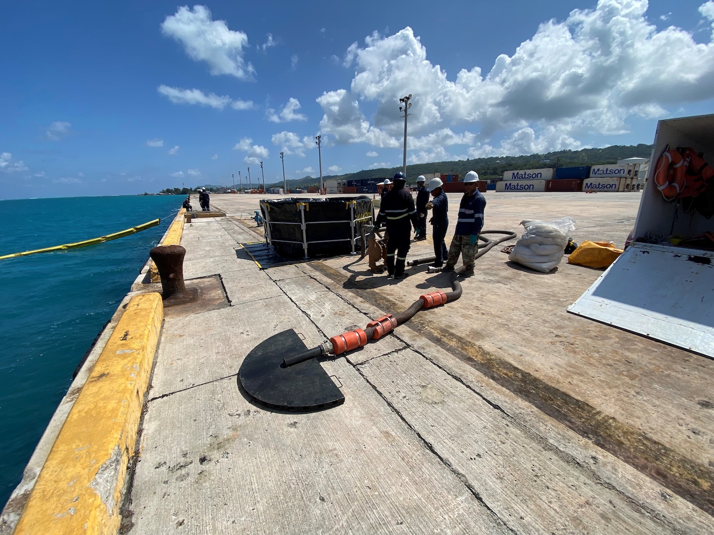 U.S. Coast Guard members observe a skimmer being set up during a Government-Initiated Unannounced Exercise (GIUE) at Mobil Saipan on Feb. 29, 2024, in Saipan, Commonwealth of the Northern Mariana Islands. The primary goal of a GIUE is to ensure that the plan holder can effectively implement their response plan during a marine environmental response scenario. (U.S. Coast Guard photo by Lt. Justin Miller)