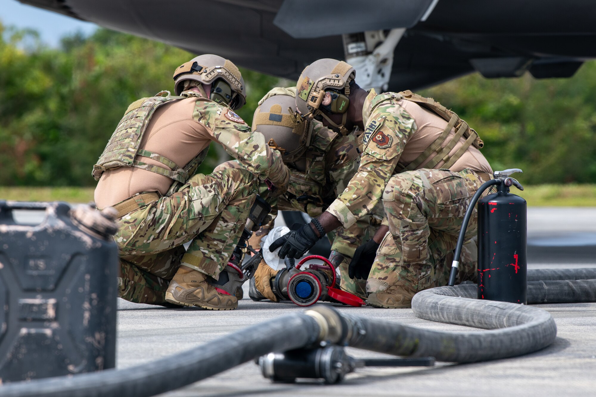 Three Airmen work with a hose.