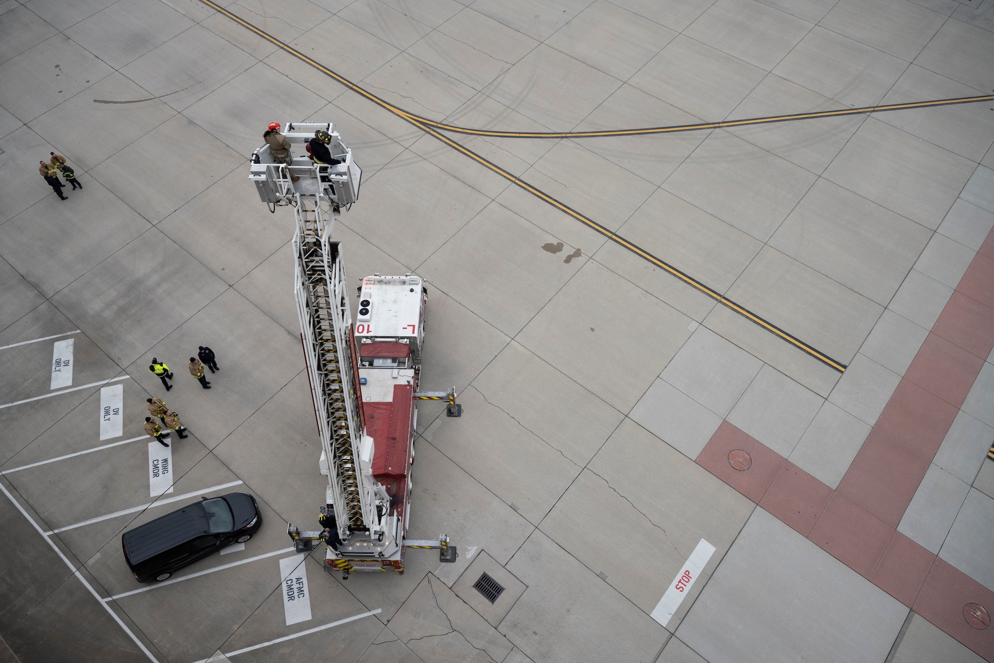 A male fireman and female military member evacuate a tower using a firetruck ladder's platform.