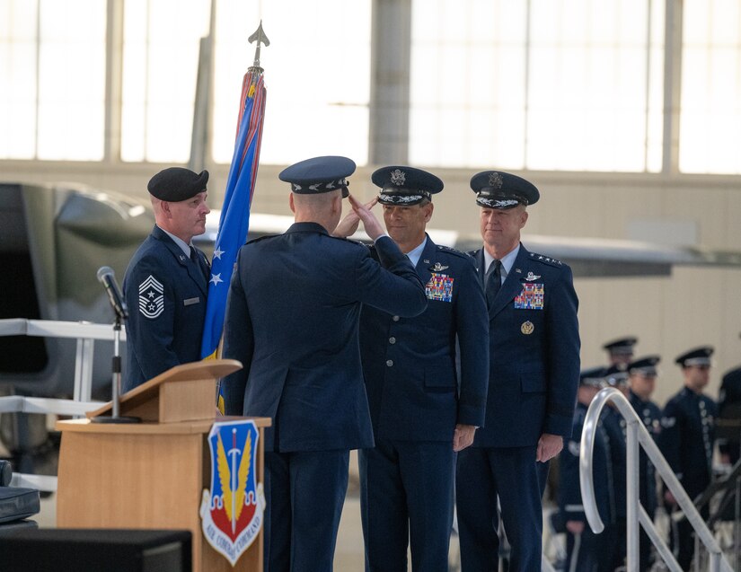 Two Air Force officers salute each other flanked by two others next to a lectern.