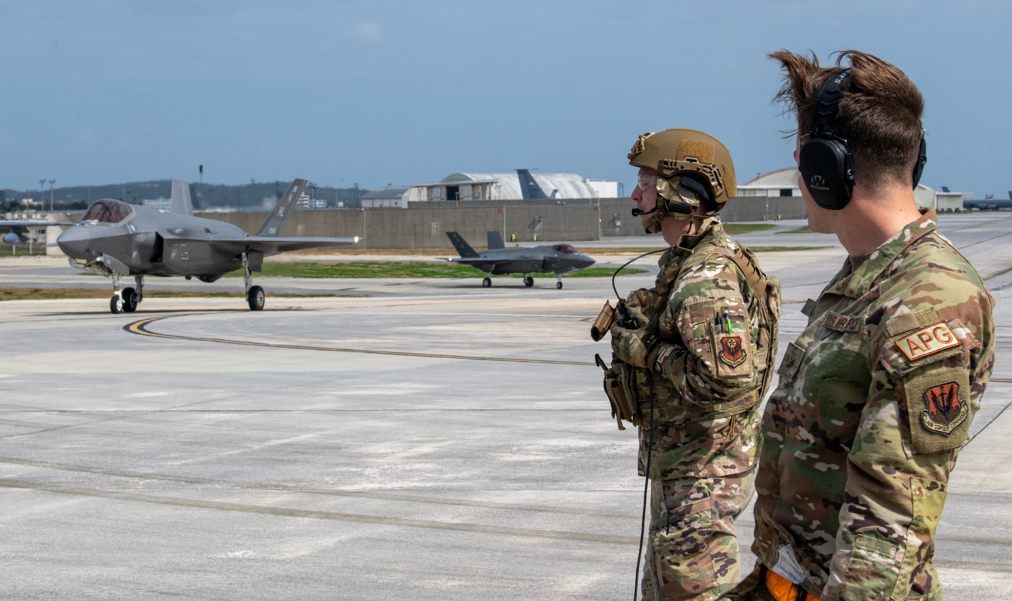 Two Airmen watch a fighter jet Taxi