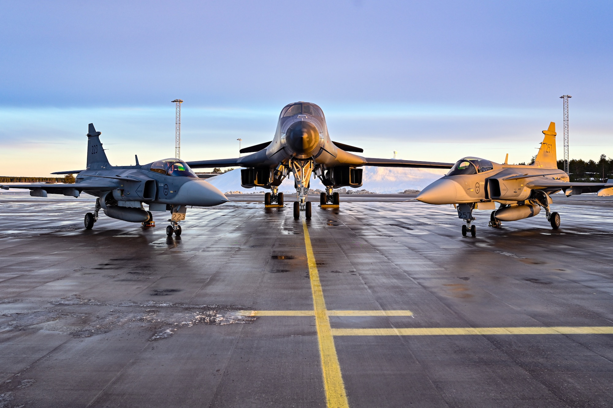 A U.S. Air Force B-1B Lancer assigned to the 28th Bomb Wing, Ellsworth Air Force Base, South Dakota, sits on a landing pad alongside two Saab JAS 39 Gripens at Luleå-Kallax Air Base, Sweden, Feb. 26, 2024, during Bomber Task Force 24-2. BTF missions enable crews to maintain a high state of readiness proficiency, and validate an always-ready, global strike capability. BTF operations provide U.S. leaders with strategic options to assure Allies and partners, while deterring potential adversary aggression across the globe. (U.S. Air Force photo by Staff Sgt. Jake Jacobsen)