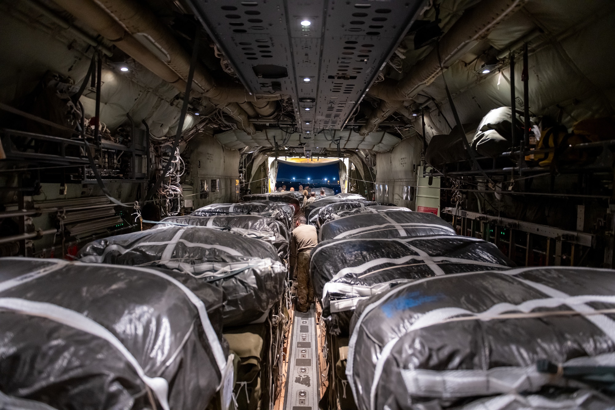 Humanitarian aid pallets rigged with parachutes for airdrop aboard a C-130J are loaded for takeoff at an undisclosed location in Southwest Asia.