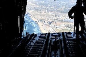 A loadmaster releases humanitarian aid pallets of food over Gaza.