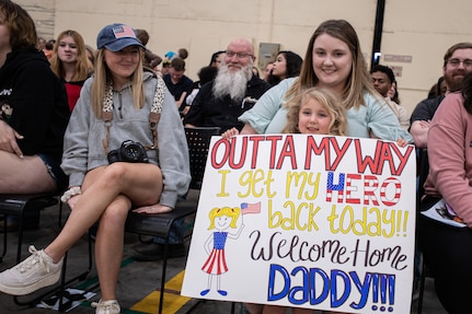 The family of a Task Force Tomahawk member holds up a sign at the Task Force Tomahawk welcome home ceremony at Will Rogers Air National Guard Base in Oklahoma City, Feb.  23, 2024. Task Force Tomahawk returned from a nine-month deployment in support of Combined Joint Task Force - Horn of Africa, where the Citizen-Soldiers provided security at multiple sites across the Horn of Africa as well as manned the East African Response Force. (Oklahoma National Guard photo by Anthony Jones)