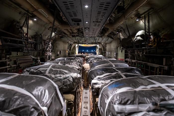 Humanitarian aid pallets rigged with parachutes for airdrop aboard a C-130J are loaded for takeoff at an undisclosed location in Southwest Asia.
