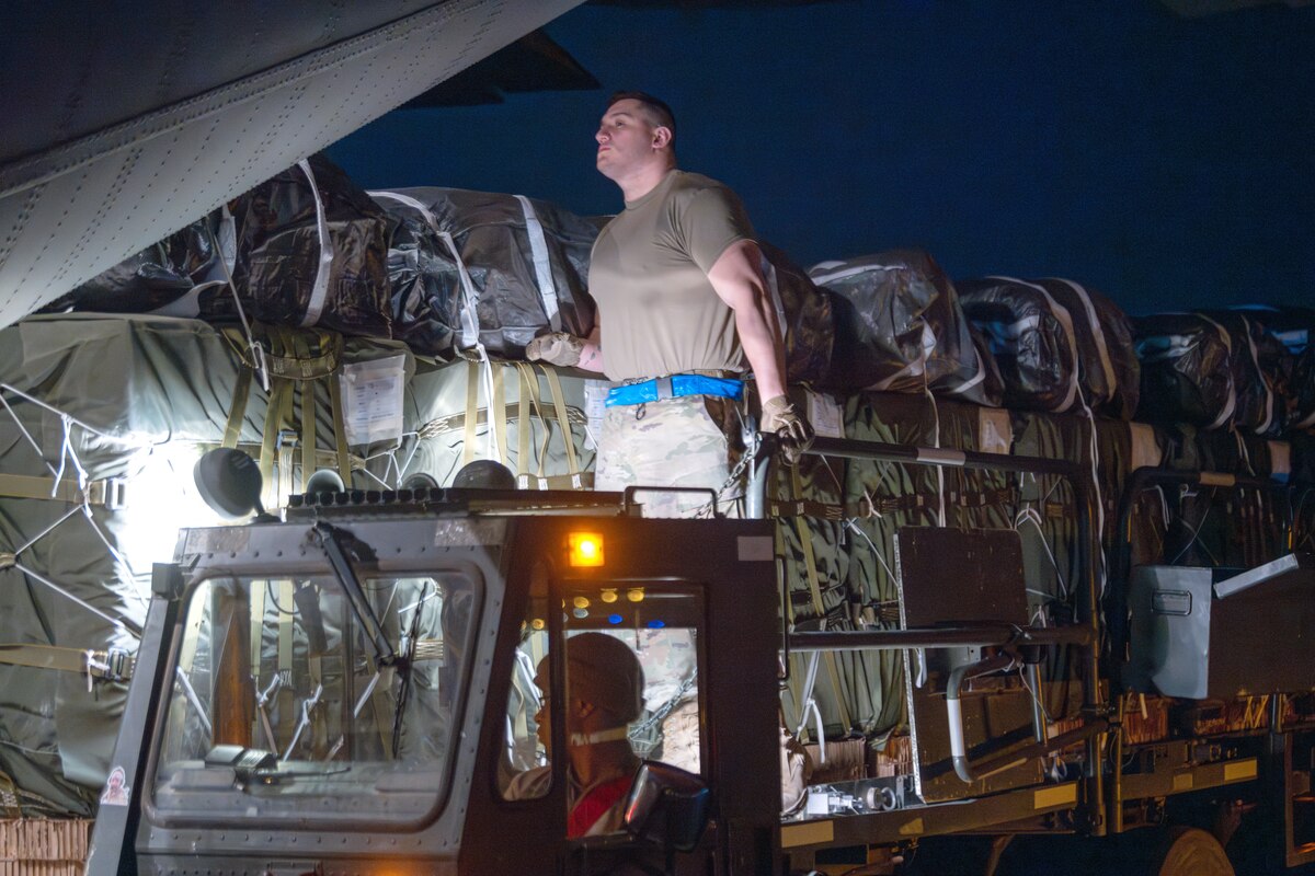 Airmen load pallets of food and water destined for an airdrop over Gaza aboard a C-130J Super Hercules