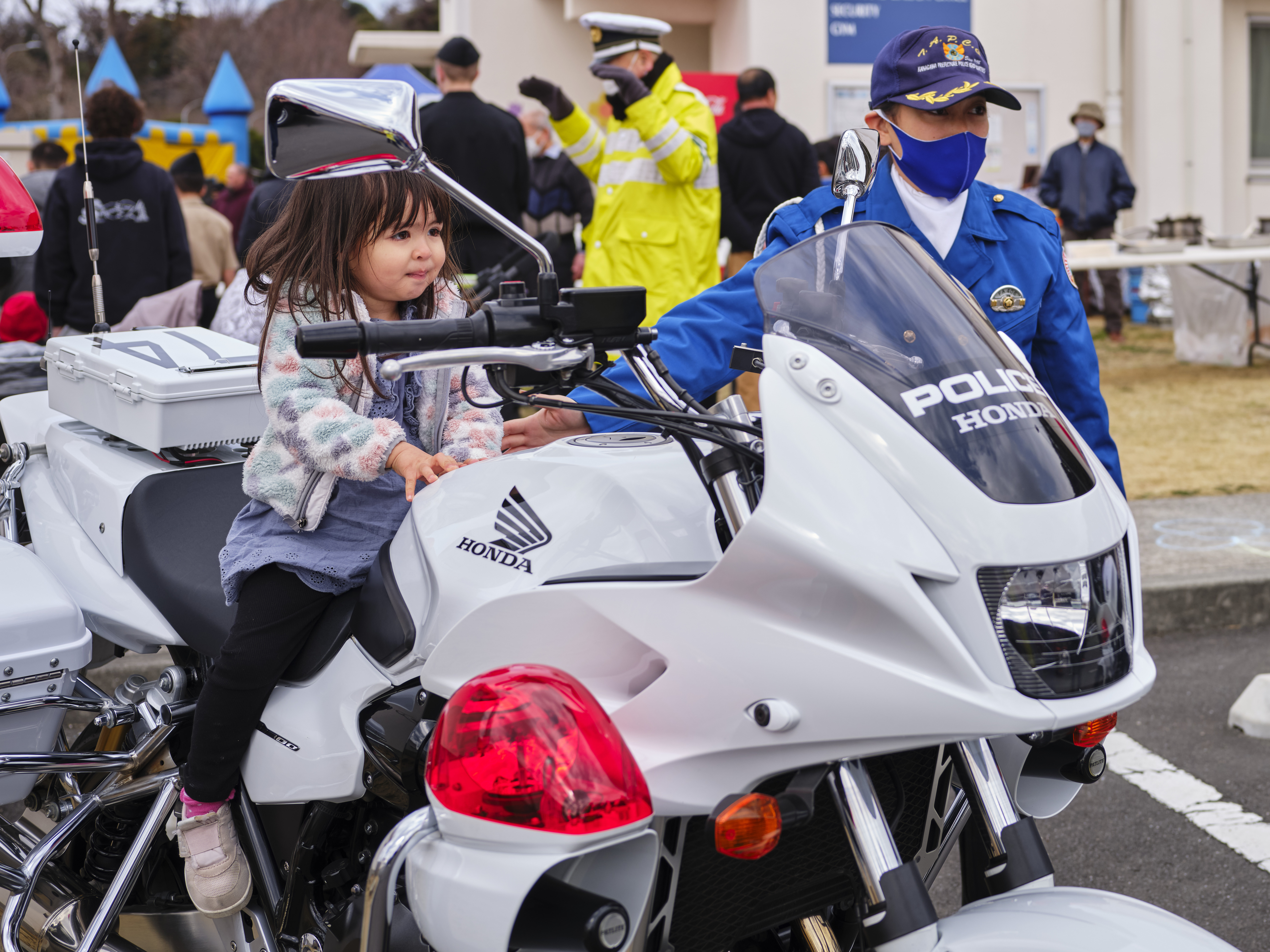 A young girl poses on a police motorcycle with a City of Zushi policewoman during the Ikego Community Outreach Fair Spring to Spring.