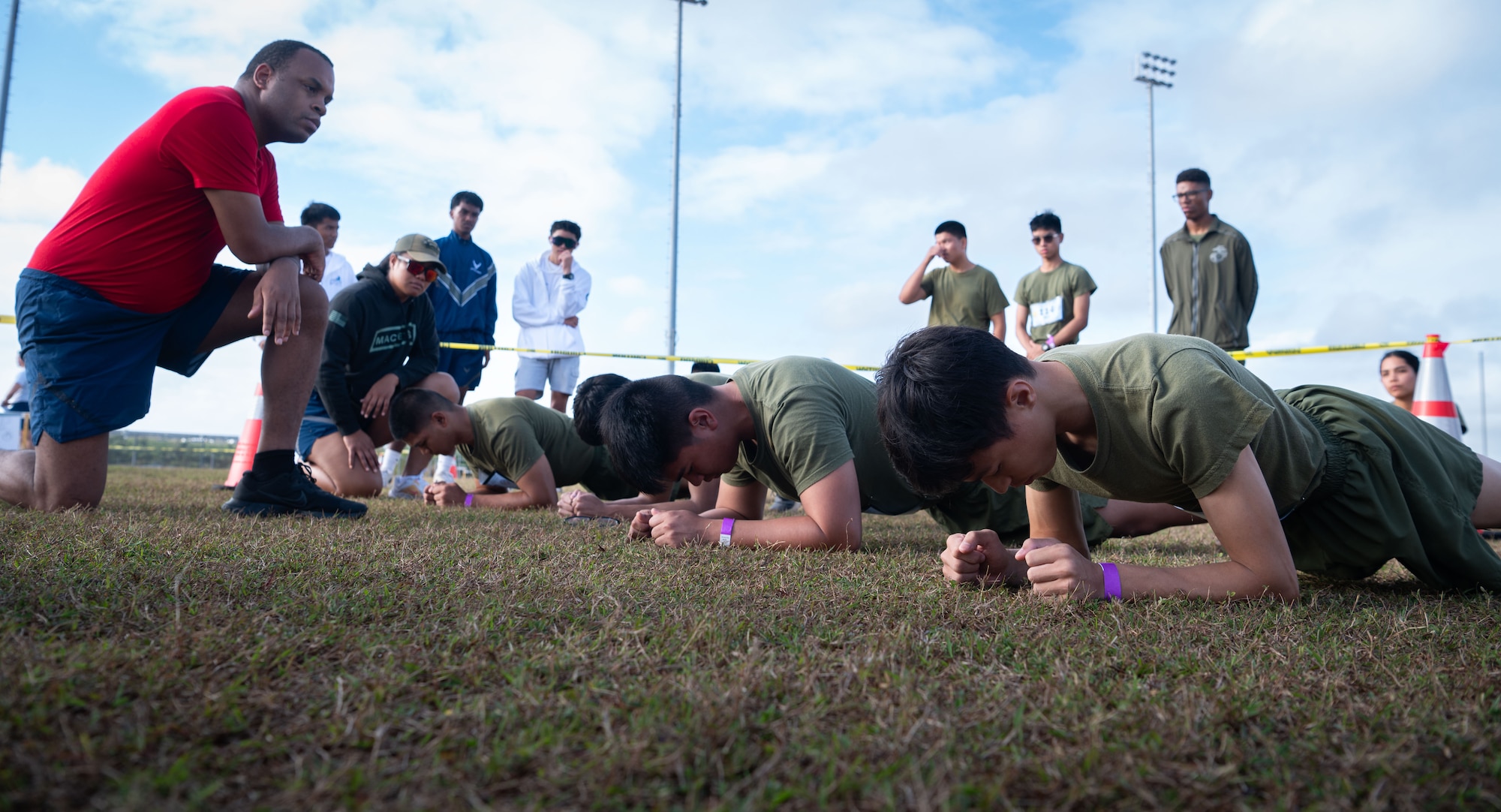 36th Wing Airmen supervise U.S. Marine Corps Junior Reserve Officer Training Corps cadets from Okkodo High School, Guam, as they compete in the plank challenge during the 3rd annual JROTC Fitness Challenge hosted at John F. Kennedy High School, Guam, Feb. 24, 2024. Six fitness challenges were overseen by a mixed team of active duty Army, Air Force, Navy and Marine service members. These volunteers ensured DoD physical fitness assessment standards were followed properly or else the cadet's efforts would not count towards their team's final score. (U.S. Air Force photo by Staff Sgt. Pedro Tenorio)