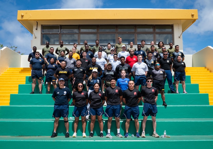 U.S. Air Force, Army, Marine Corps and Navy service members pose with Junior Reserve Officer Training Corps instructors from John F. Kennedy High School, Guam, in Tamuning, Guam, Feb. 24, 2024. These 49 volunteers made sure more than 100 cadets were able to complete all six challenges smoothly and scored fairly within DoD physical fitness assessment standards. Although the event was called a challenge, the true purpose of the JROTC Fitness Challenge is to allow natural mentoring opportunities between the volunteers and cadets. (U.S. Air Force photo by Staff Sgt. Pedro Tenorio)