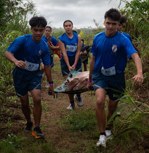 U.S. Air Force Junior Reserve Officer Training Corps cadets from John F. Kennedy High School, Guam, carry a stretcher with a dummy in it during the 3rd annual JROTC Fitness Challenge hosted at JFKHS, Feb. 24, 2023. Most of the fitness challenge were actual tests that are conducted during DoD physical fitness assessments, i.e. push-ups and sit-ups. The addition of the equipment trail run challenge was to educate the cadets on what working in/carrying military equipment would feel like in the field. This event is also the only pure team event in which the team's fitness score is based on the whole team crossing the finish line. (U.S. Air Force photo by Staff Sgt. Pedro Tenorio)