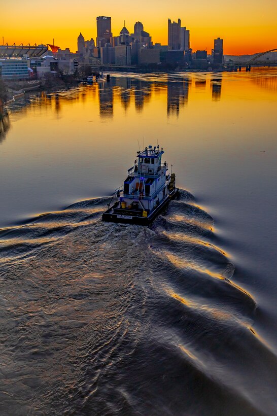 Towboats moving barges on the Ohio River in Pittsburgh at sunrise.