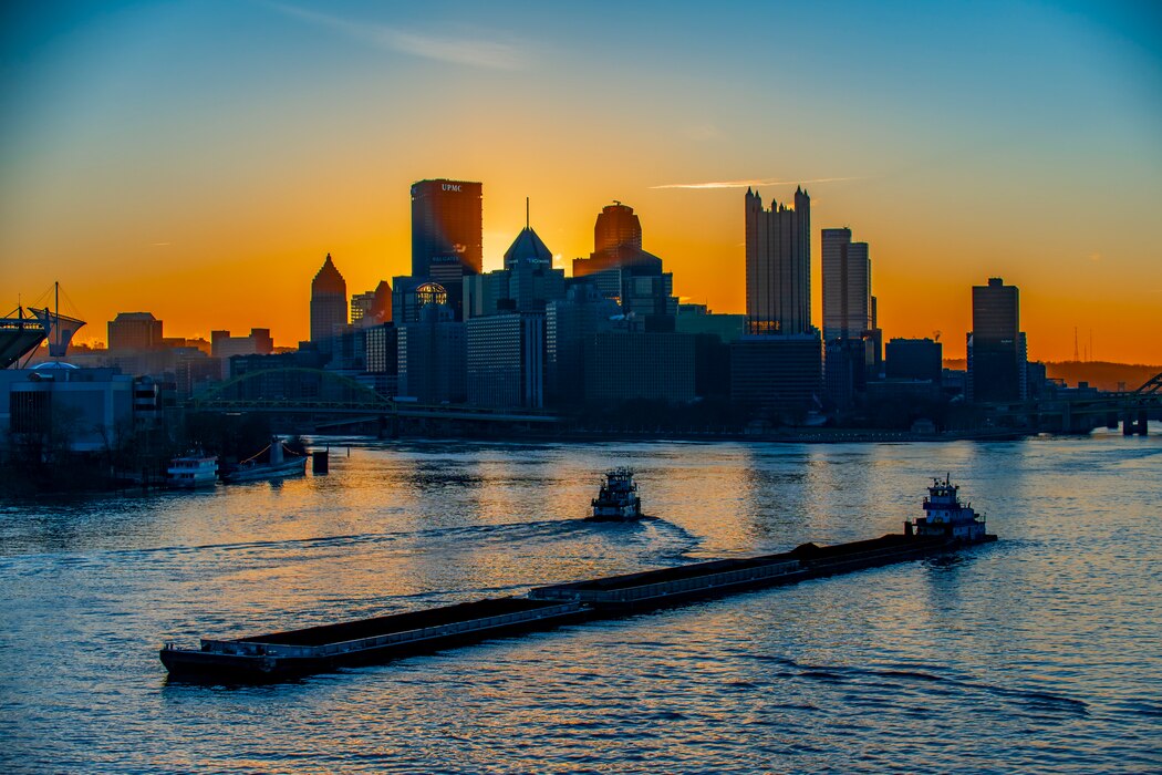 Towboats moving barges on the Ohio River in Pittsburgh at sunrise.