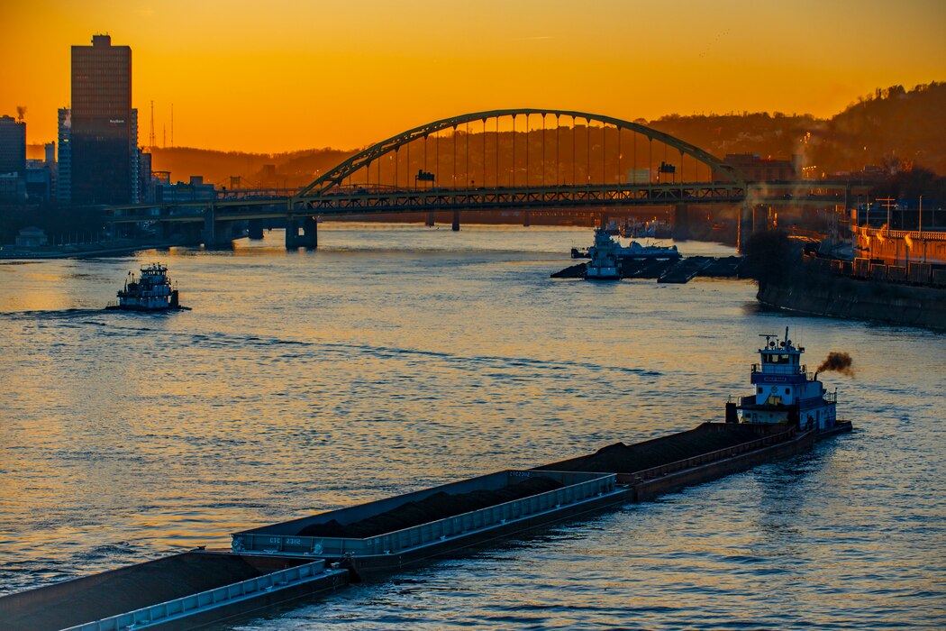 Towboats moving barges on the Ohio River in Pittsburgh at sunrise.