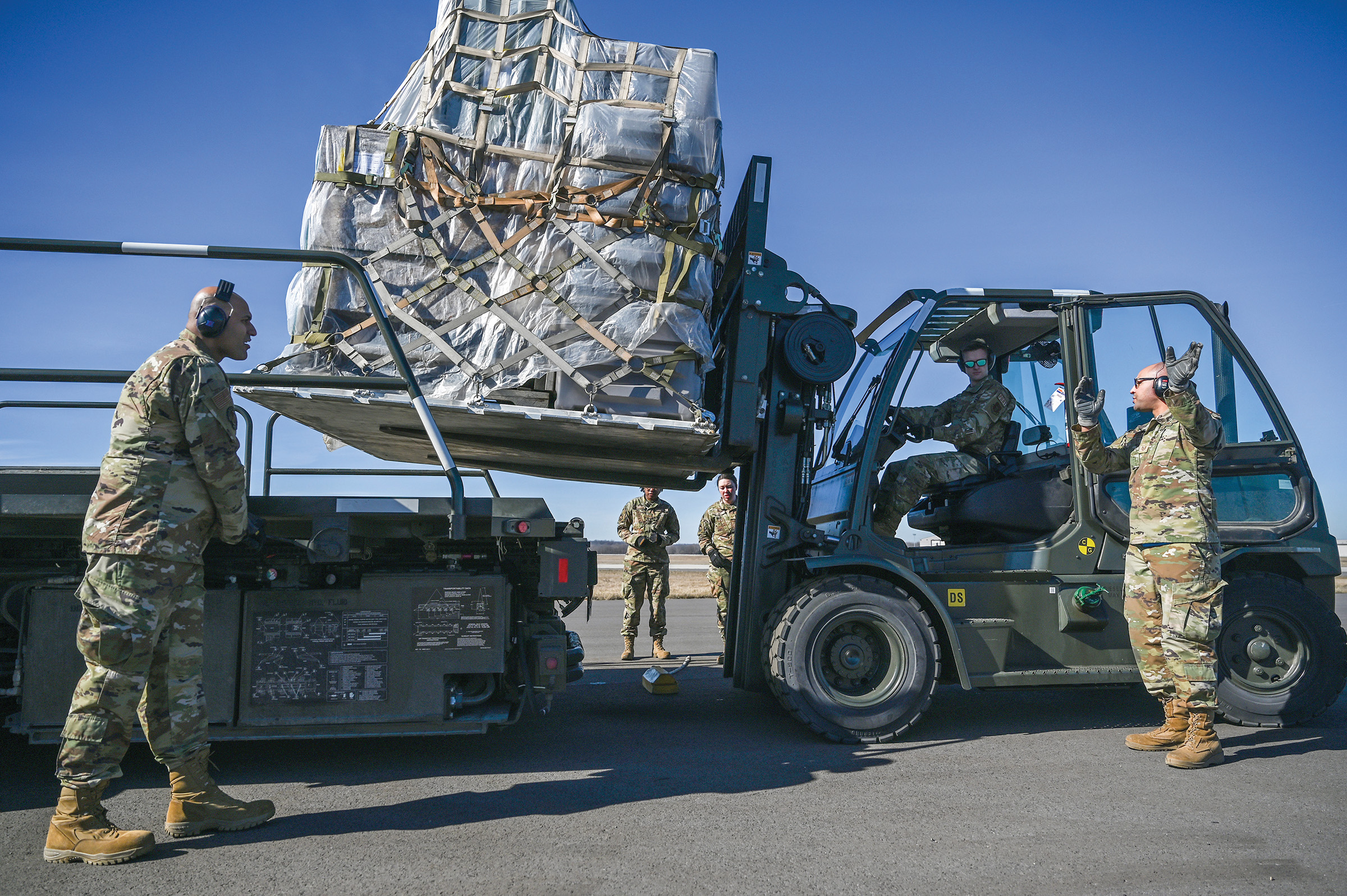 Members of the 87th Aerial Port Squadron guide a forklift carrying cargo during the Port Dawg Challenge, Feb. 4, 2024. The PDC is an opportunity for Airmen to demonstrate aircraft loading operations skills.