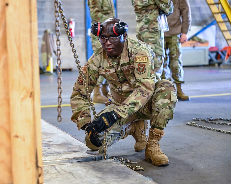 Senior Airman Kingsley Oteng, 87th Aerial Port Squadron passenger services representative, fastens a chain to secure a load during the Port Dawg Challenge at Wright-Patterson Air Force Base, Feb. 4, 2024.