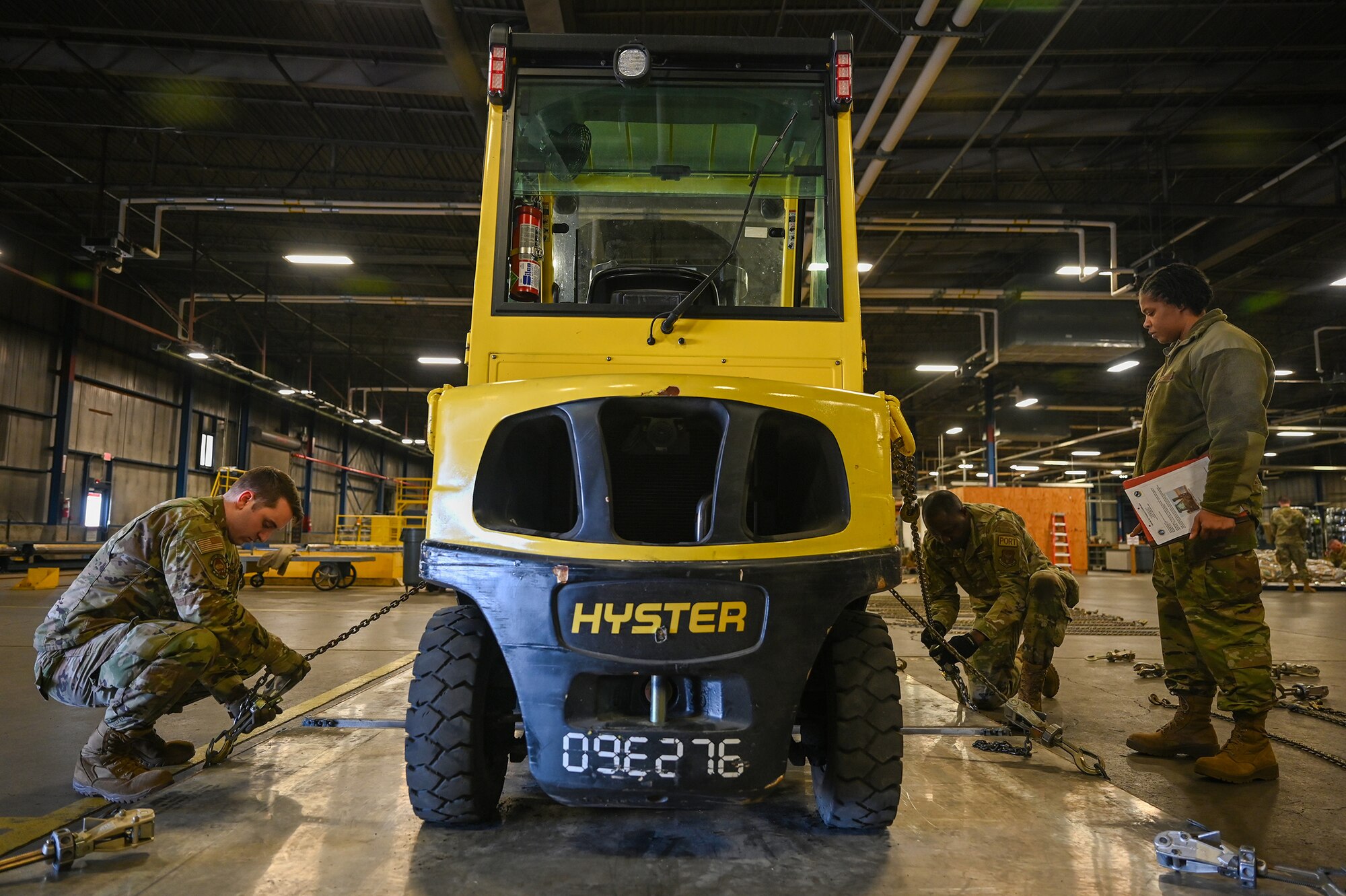 Staff Sgt. Matthew Colonna, 87th Aerial Port Squadron air freight representative, and Tech. Sgt. Oyekola Mustapha, 87th APS cargo processing representative, secure a forklift onto a pallet as Master Sgt. Bakiden Gordon, 87th APS passenger services supervisor, observes during the Port Dawg Challenge, Feb. 4, 2024.