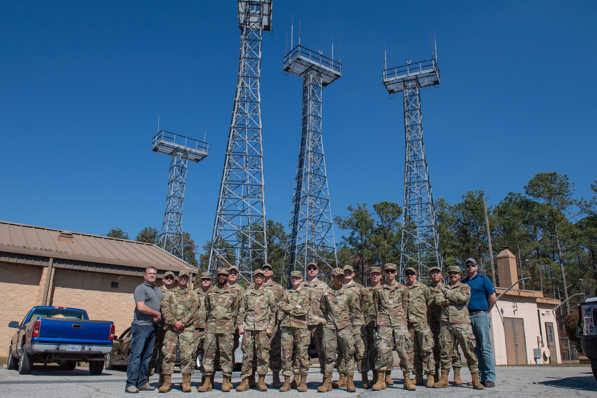 Airmen pose for a group photo in front a radio towers
