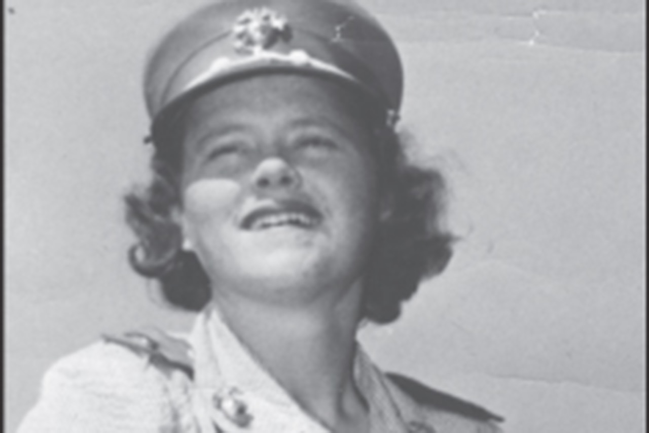 A person wearing a Marine uniform smiles for the camera in a black and white photo.