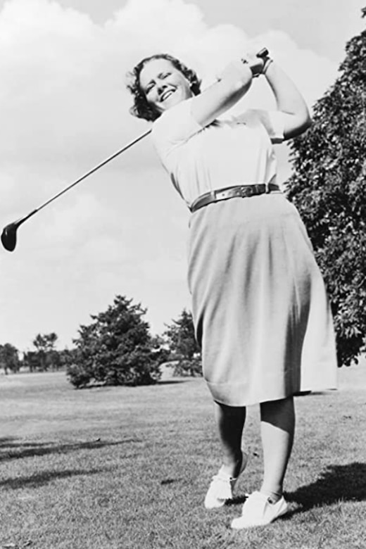 A person swings a golf club in a black and white photo.