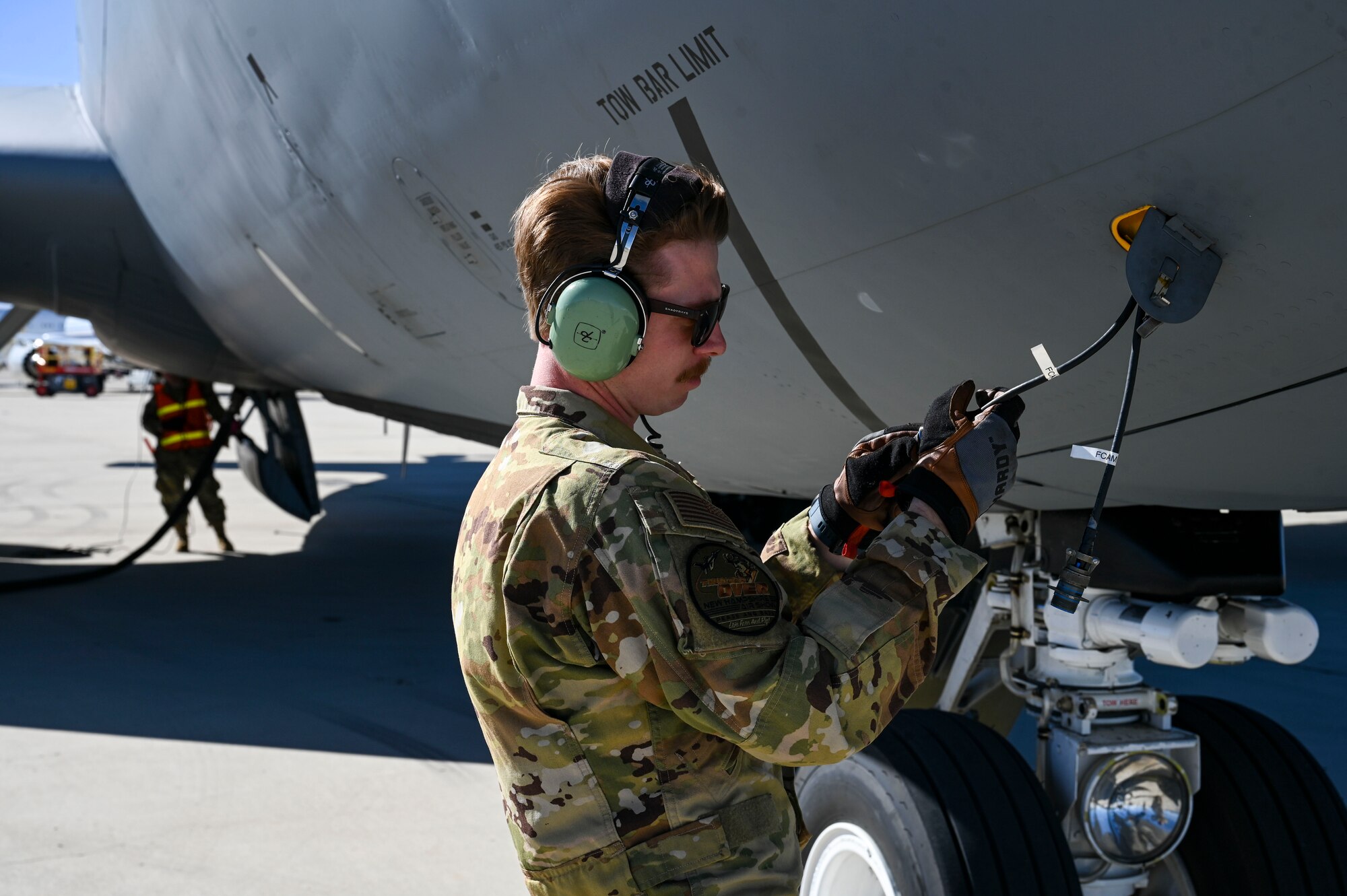 An Airman hooks a cable up to a jet.