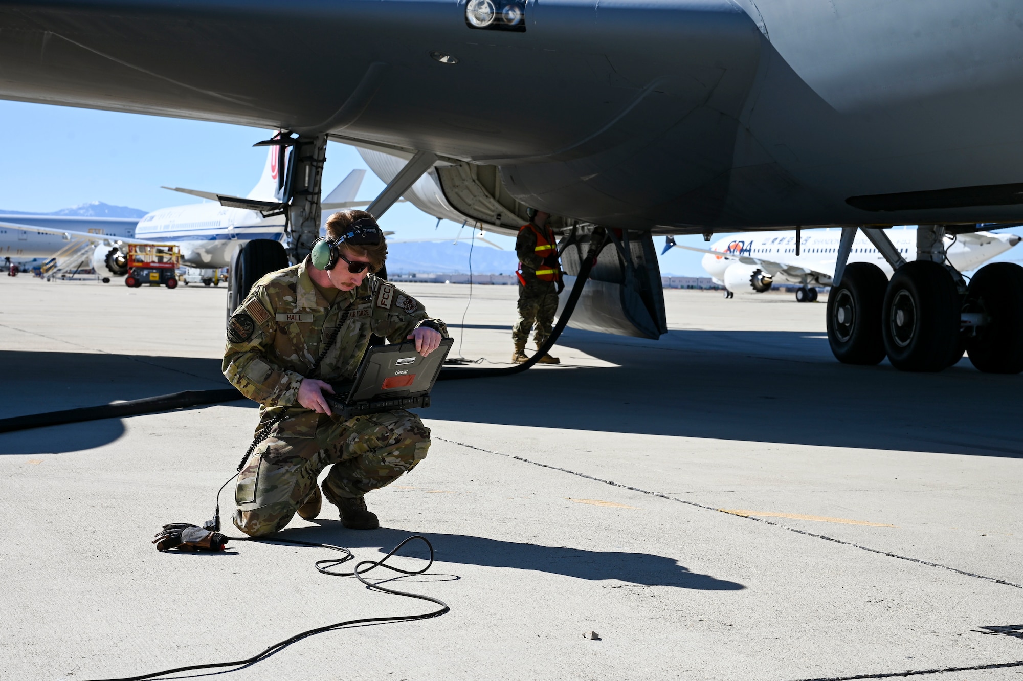 An Airman looks at a computer in front of a jet.