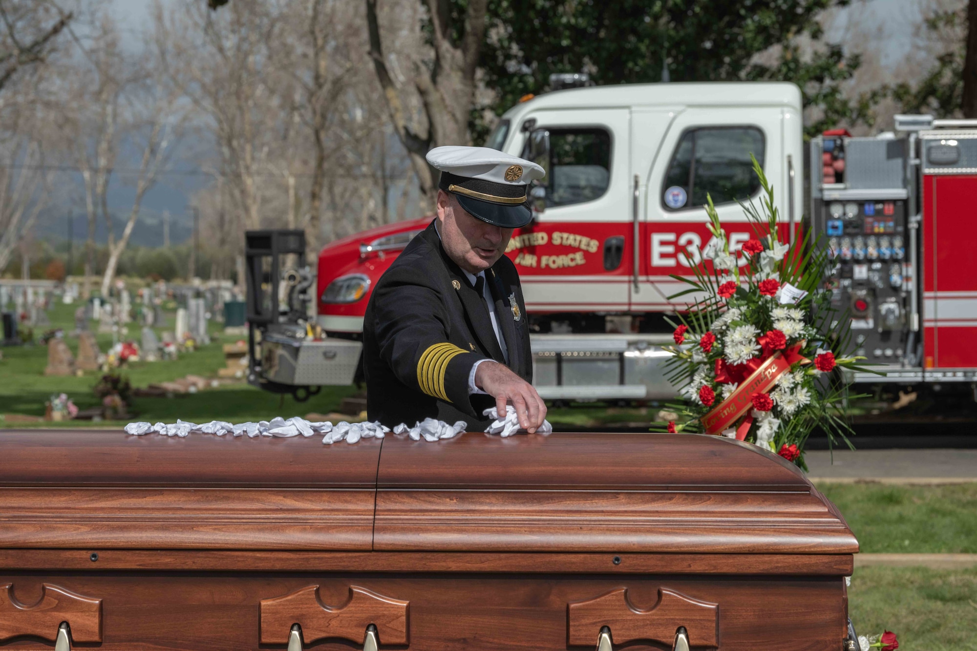 Former fire chief lays white glove on casket.